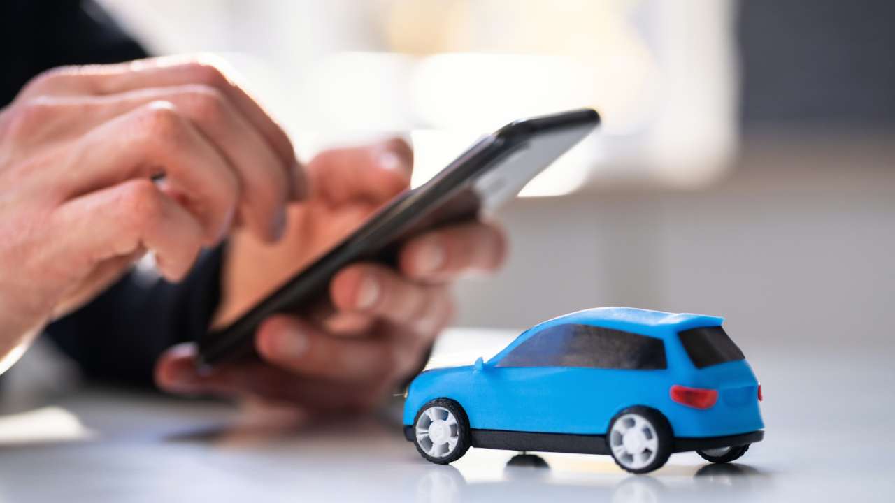 iemand met een telefoon in de hand en mini auto op tafel