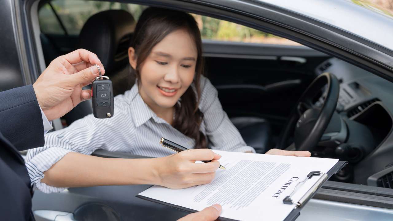 mevrouw in e auto met een contract en iemand die een autosleutel wilt geven