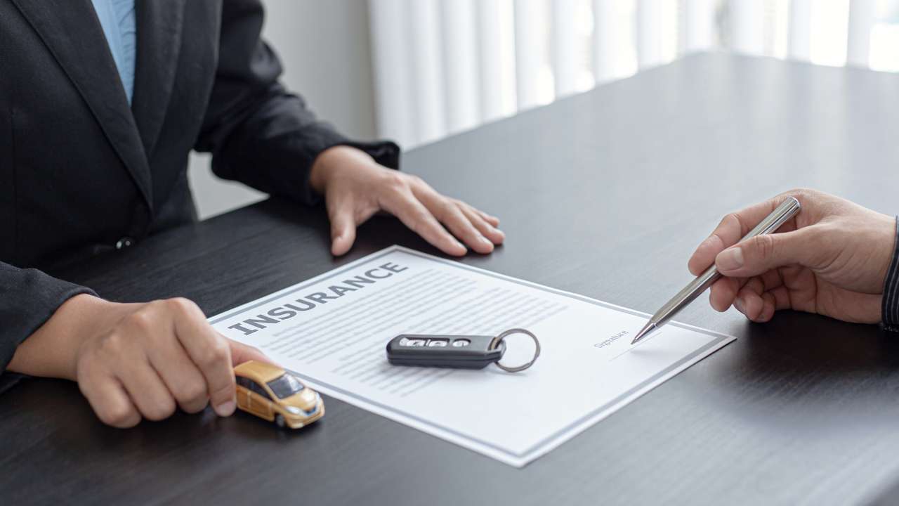 min autoverzekering contract en autosleutels op tafel tussen twee personen